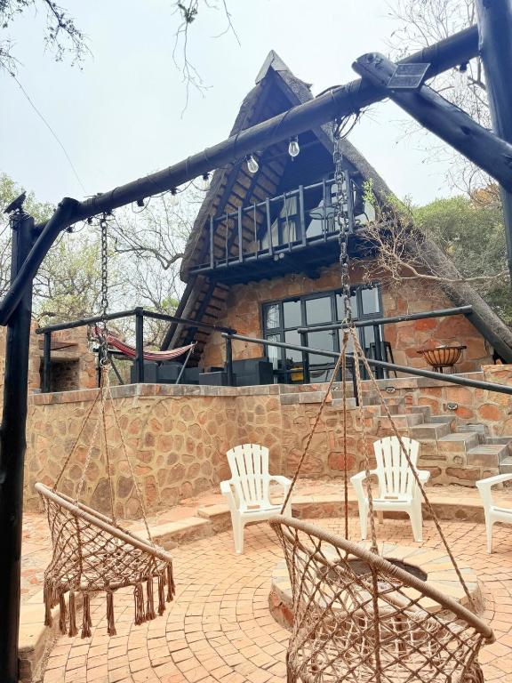 a patio with swings and chairs in front of a building at Picturesque 82 in Buffelspoort