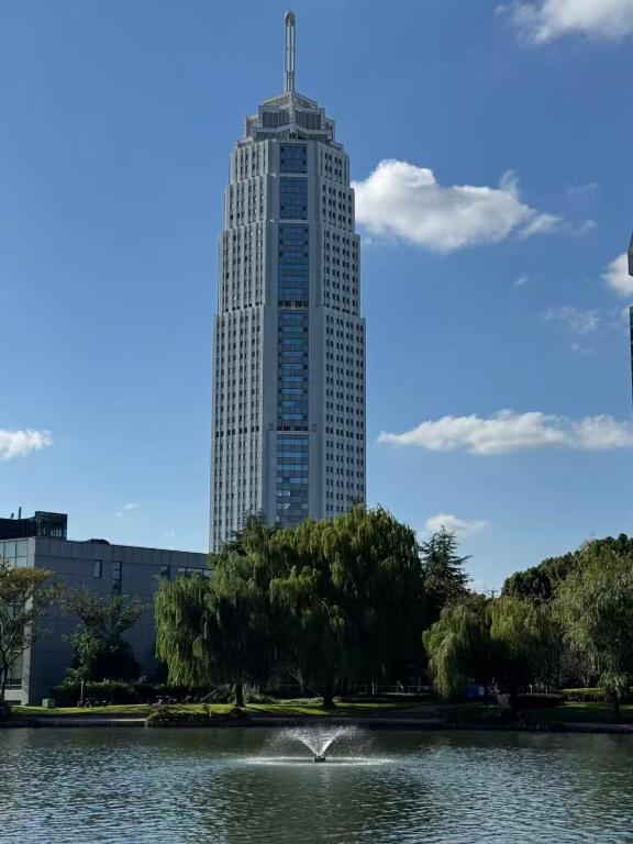 a tall building with a pond in front of it at Ramada Plaza Pudong Shanghai in Shanghai
