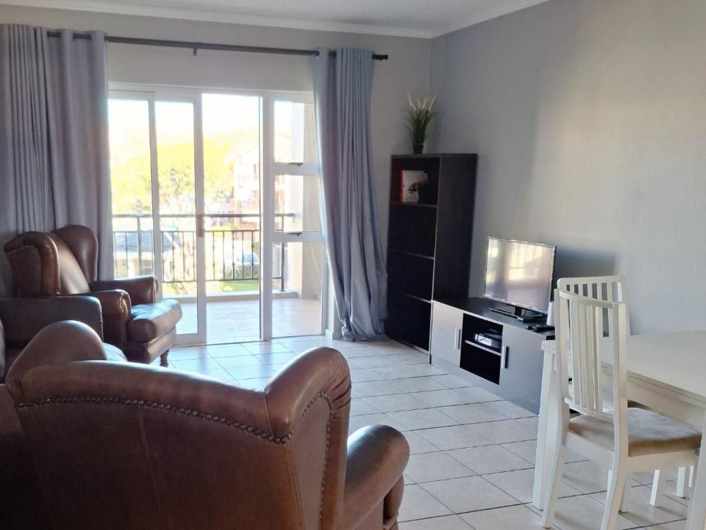 a living room with a table and chairs and a television at Merve's Place - Portobelo 48 in Mossel Bay