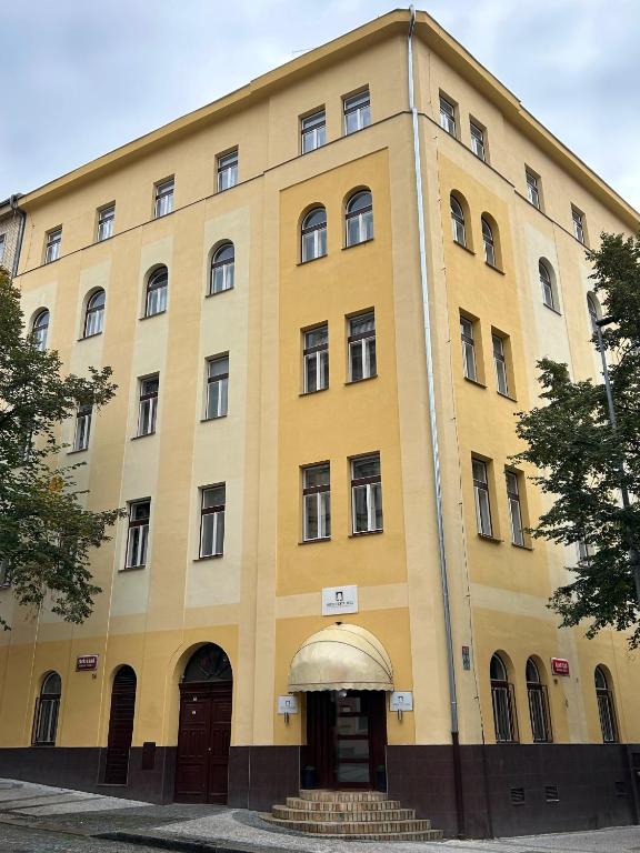 a large yellow building with doors and windows at Hotel City Bell in Prague
