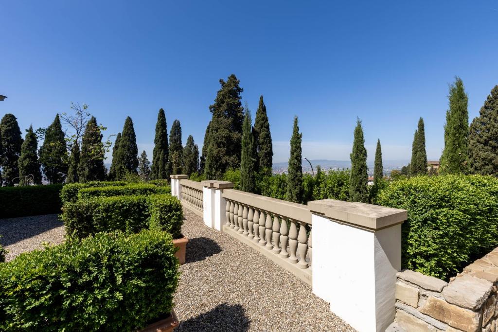 a white fence in a garden with trees at Lo Studiolo Fiesole in Fiesole