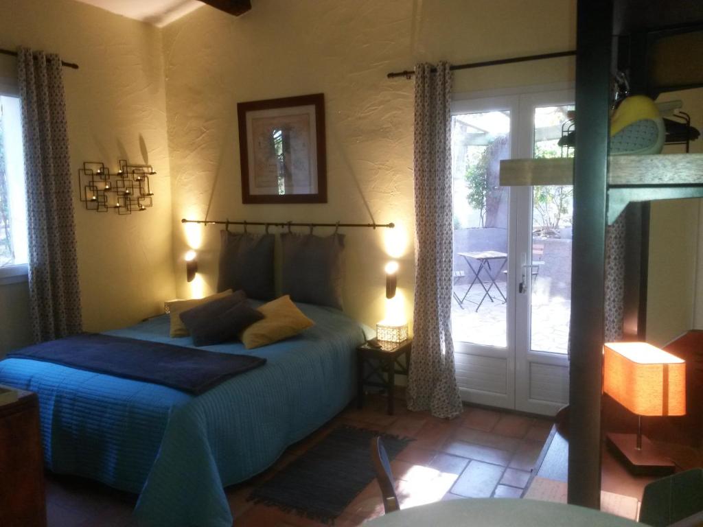 a bedroom with a blue bed and a sliding glass door at Chambres d'Hôtes Les Mayombes in Roquebrune-sur-Argens