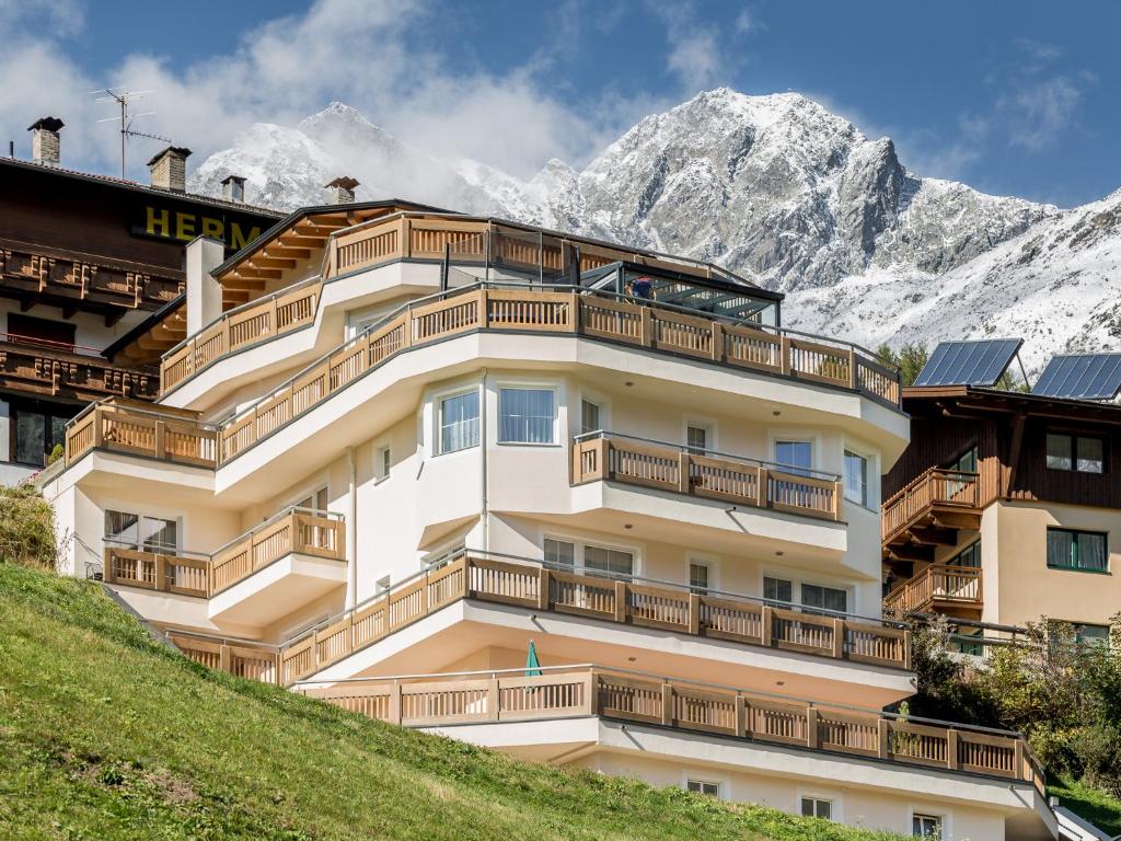 a building on a hill with mountains in the background at Panoramablick Sölden in Sölden