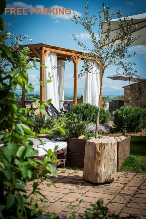 a garden with a wooden pergola and a tree stump at Palazzo del Papa Country Suites-5 mins from Siena & Chianti Views in Siena