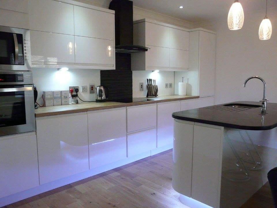 a kitchen with white cabinets and a black counter top at Langley Cottage in Wick