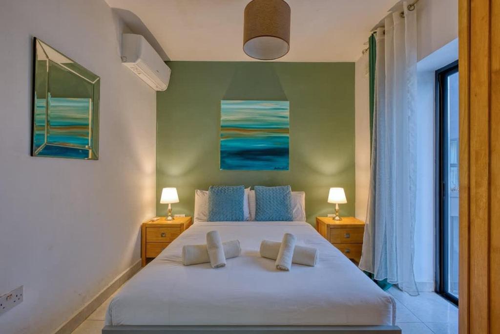 a bedroom with a large white bed with two night stands at 1-Bed Suite Near Spinola Bay in Paceville