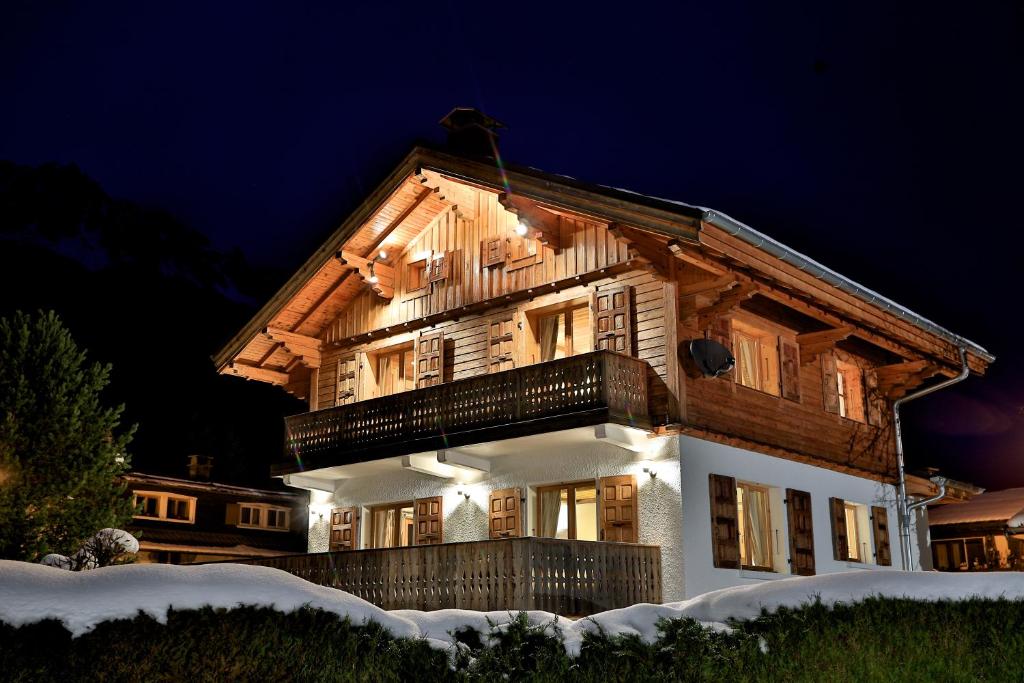 a large wooden house with a balcony at night at Chalet Cristalliers - 5 Bedroom luxury chalet in central Chamonix with log fire and hot tub in Chamonix
