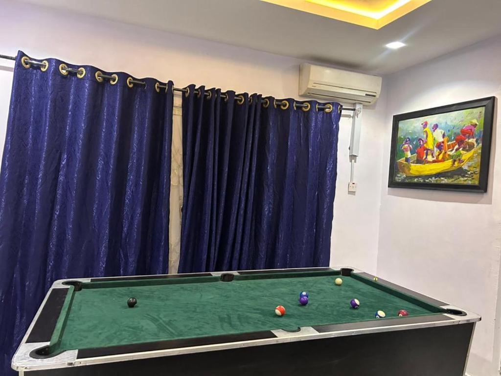 a pool table in a room with blue curtains at Apartment in Alakuko in Akinde