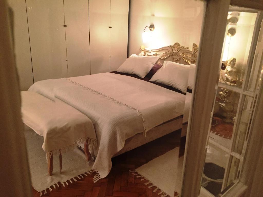 Apartment Baroque في بلغراد: غرفة نوم بسرير وملاءات بيضاء ومرآة