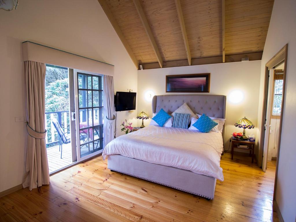 a bedroom with a large bed and a balcony at Olinda Country Cottages in Olinda