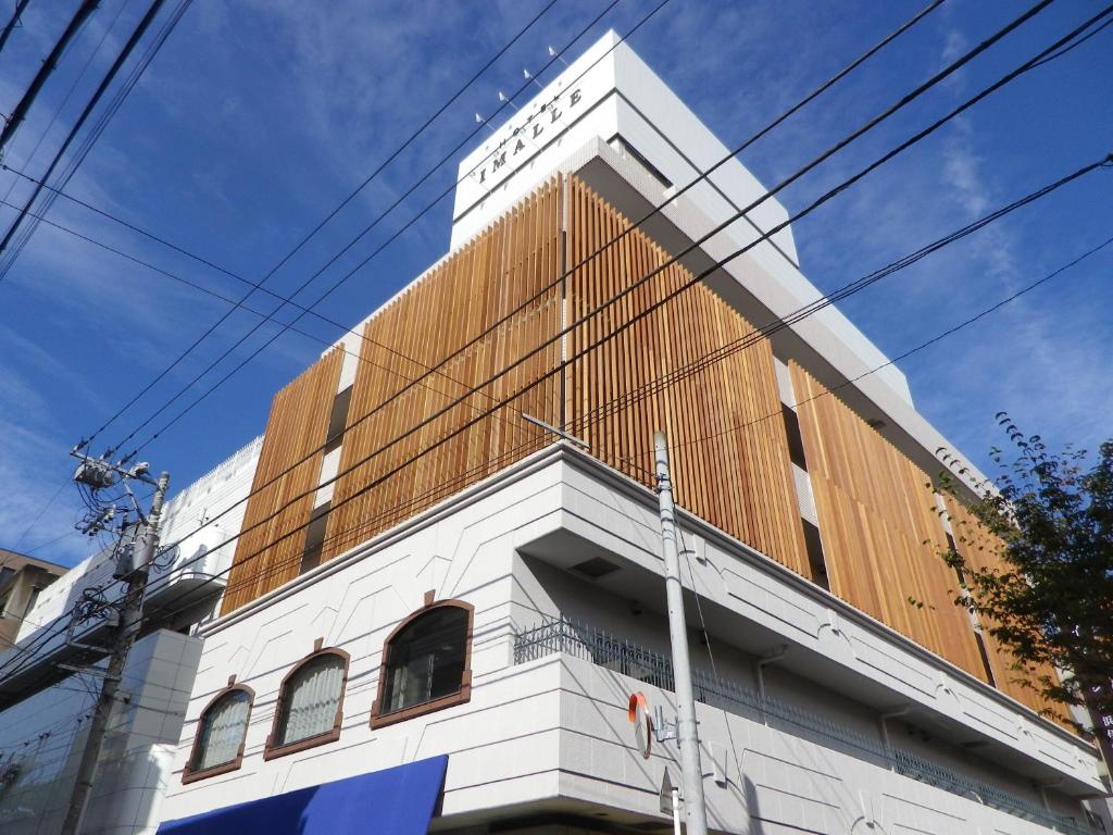 a tall white building with a brown at Hotel Imalle Yokohama Isezakicho in Yokohama