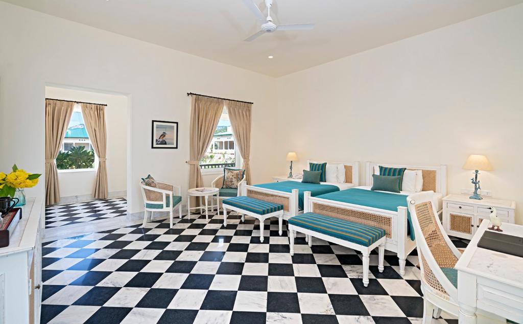 a bedroom with two beds and a checkered floor at Tree of Life Sariska, Manor in Tehla