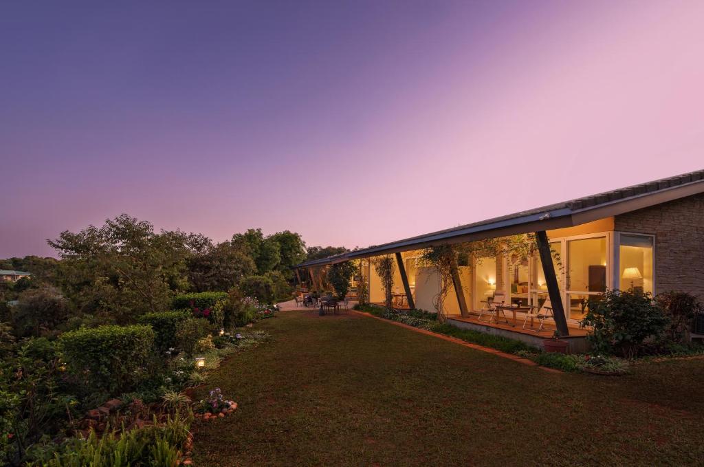 a house with a large yard next to a building at SaffronStays Vinayalam in Mahabaleshwar