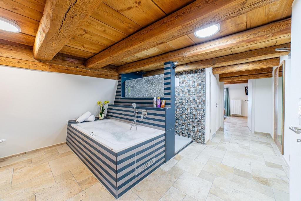 a bathroom with a tub in a room with wooden ceilings at Gästehaus Hopfenperle in Spalt