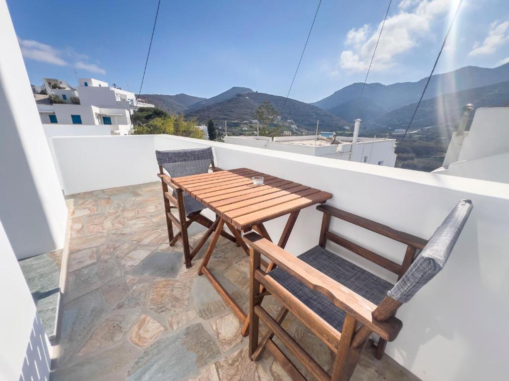 a wooden table and chairs on a balcony with mountains at Amorgona Apartments in Katapola