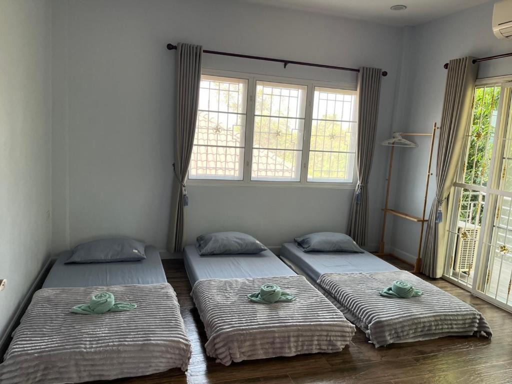 three beds in a room with two windows at baan wongsupar in Suan Phung