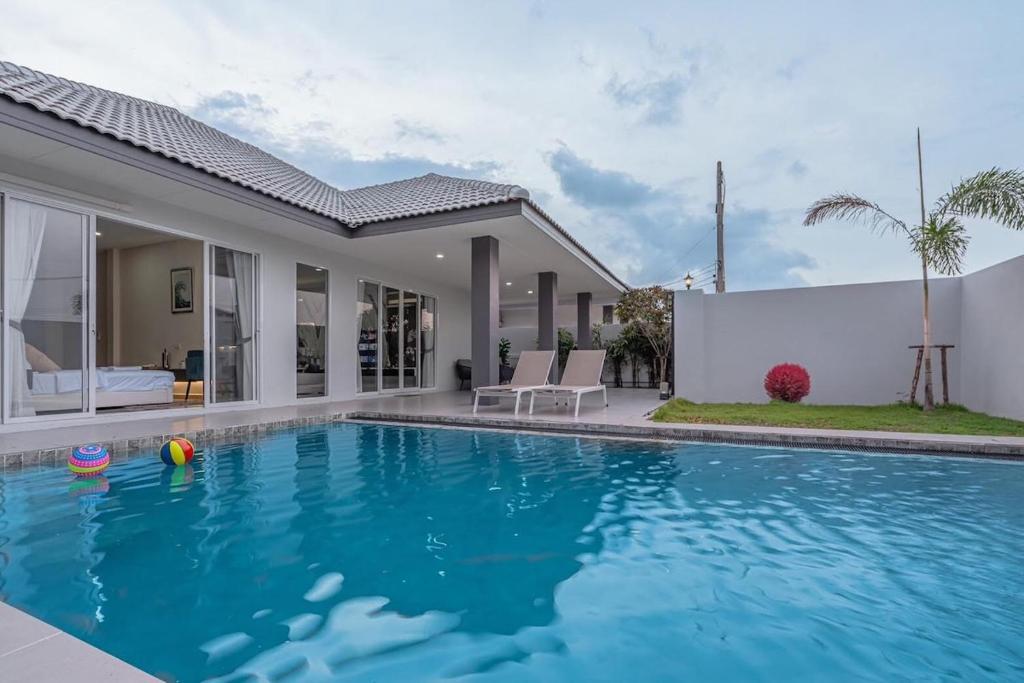 a swimming pool in front of a house at 63 Jomtien Beach villa วิลล่าใกล้หาดจอมเทียน 這棟別墅距離海灘不遠 in Jomtien Beach