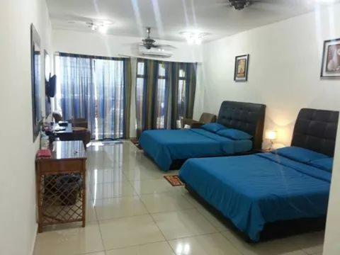 a bedroom with two blue beds and a room with windows at Homestay KBCC in Kota Bharu