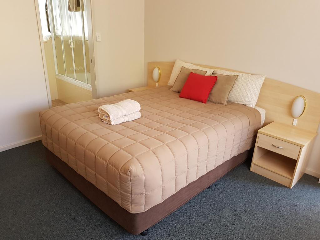 Una cama en una habitación con una almohada roja. en Central Motel Nelson Bay en Nelson Bay