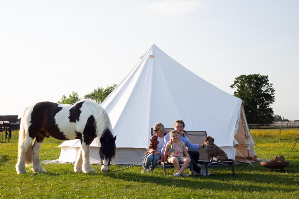 a family sitting in front of a tent with a horse at Glamping met paarden in Nieuwerkerken