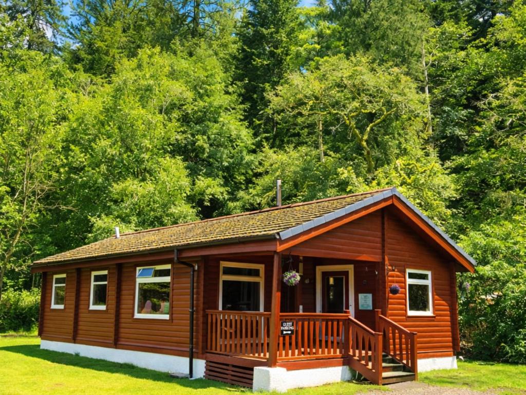 a small cabin with a deck in the grass at Antler Lodge Traditional Log Cabin in Dunoon
