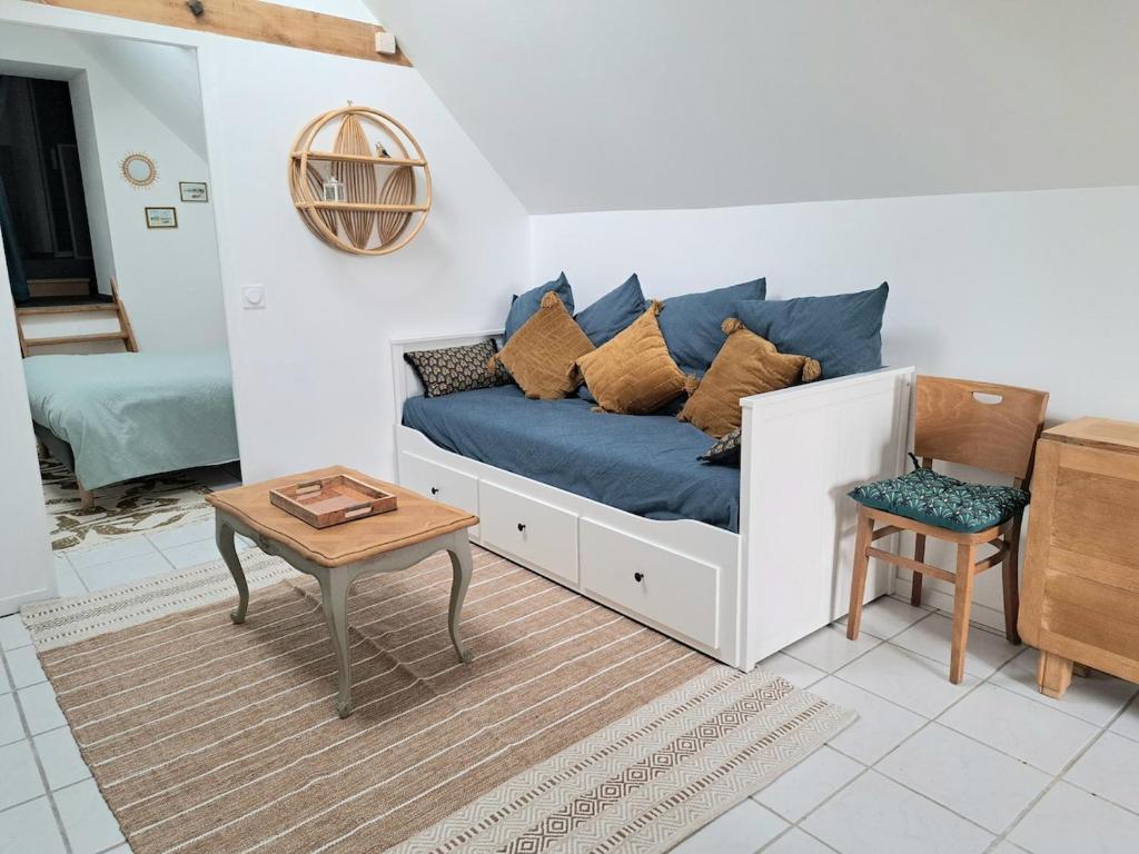a living room with a blue couch and a table at Aux Rives Tranquilles, appartement bord de Loire avec vue in Les Rosiers