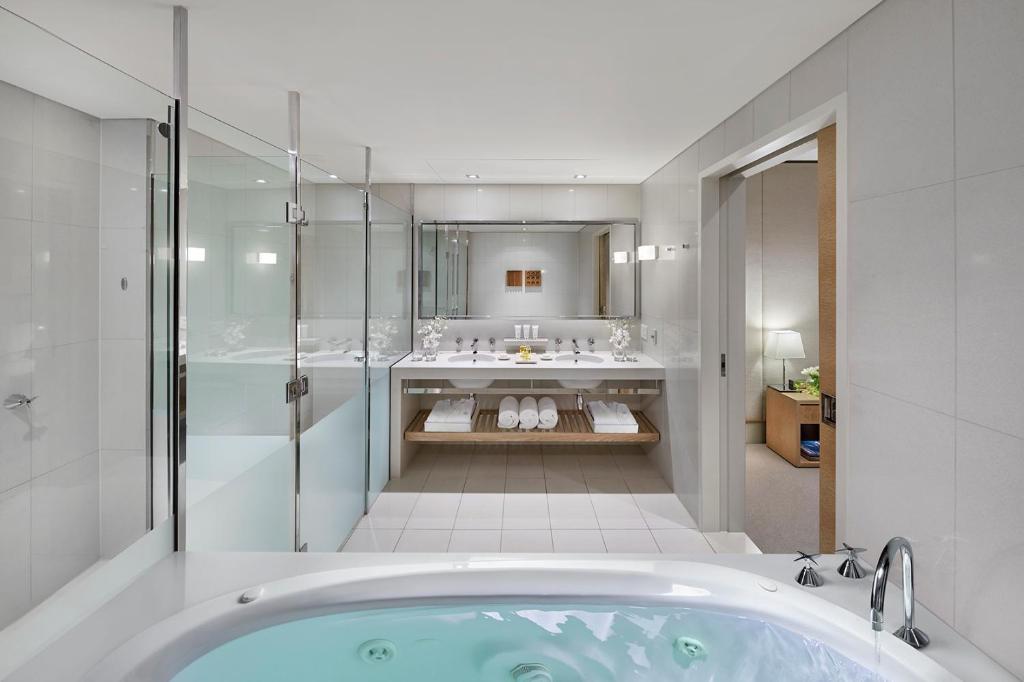a bathroom with a tub and a shower and a sink at Crown Promenade Melbourne in Melbourne
