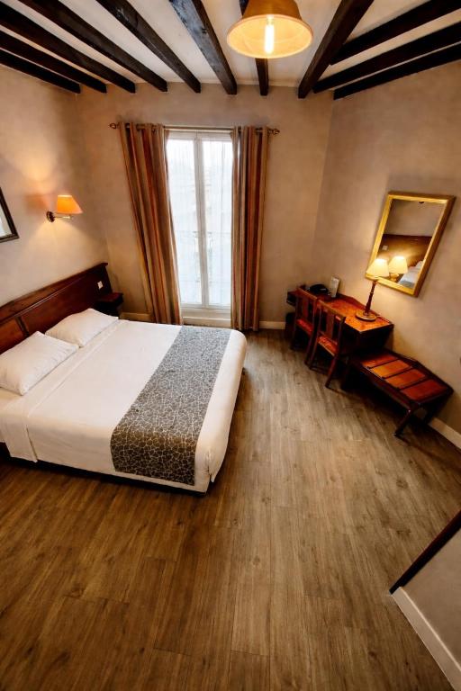 a bedroom with a bed and a desk and a window at Hotel Richmond Gare du Nord in Paris