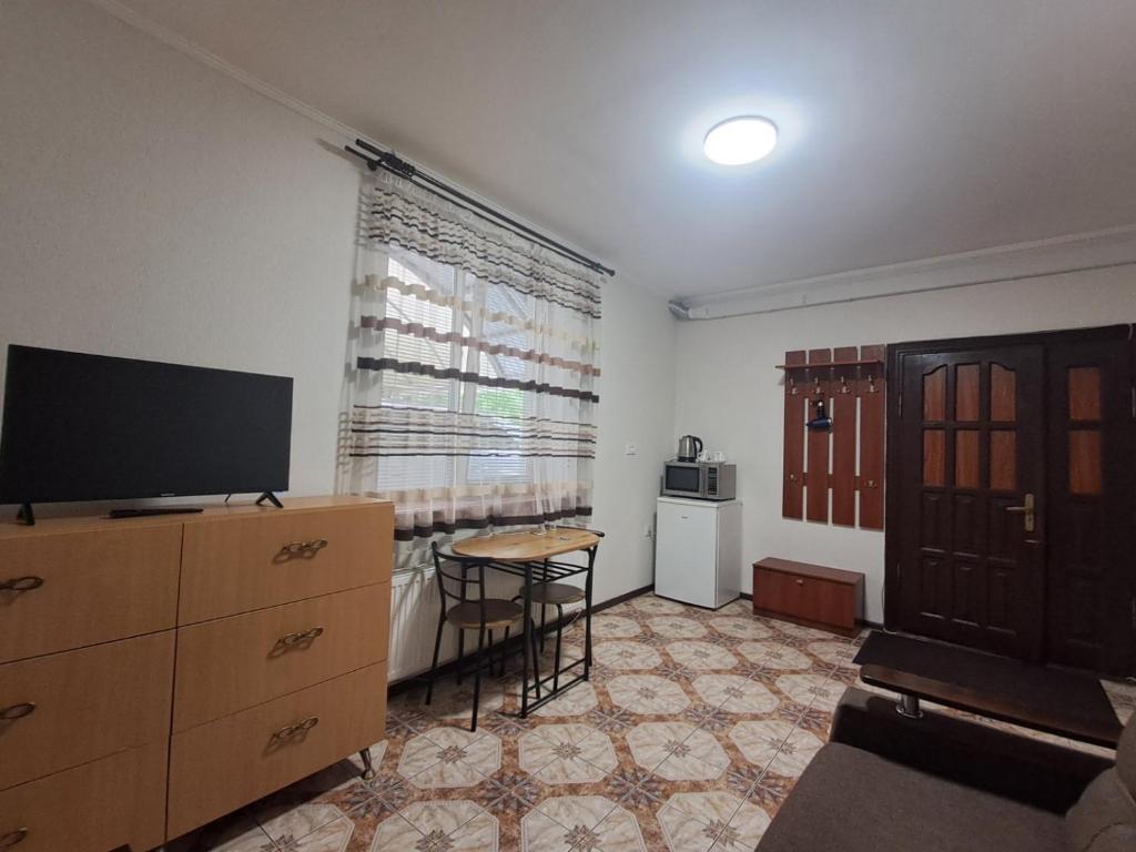 a living room with a television and a dresser with a table at Бордуляка 11 in Ternopil