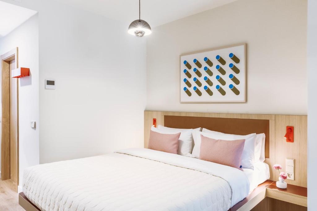 a bedroom with a large white bed with pink pillows at Numa Madrid Fuencarral in Madrid
