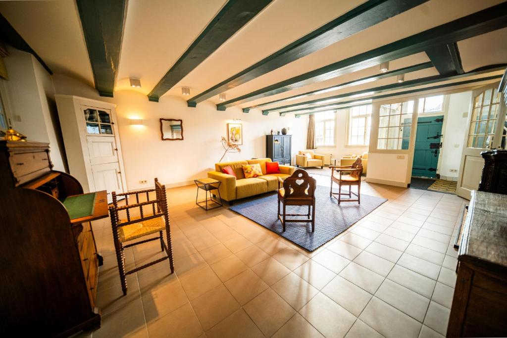 a living room with a couch and tables and chairs at Het Sluiswachtershuisje in Maassluis