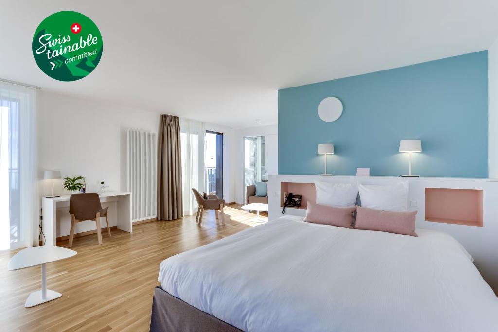 a hotel room with a large bed and a desk at Hôtel des Patients in Lausanne