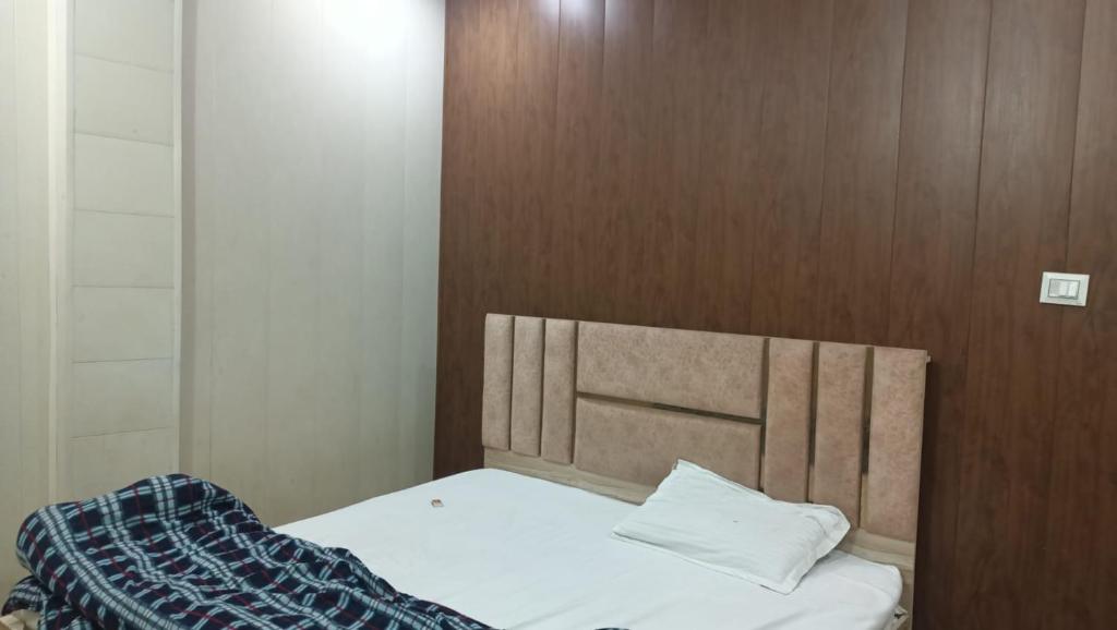 a bedroom with a bed with a wooden headboard at Firangi Chacha in Bāra Banki