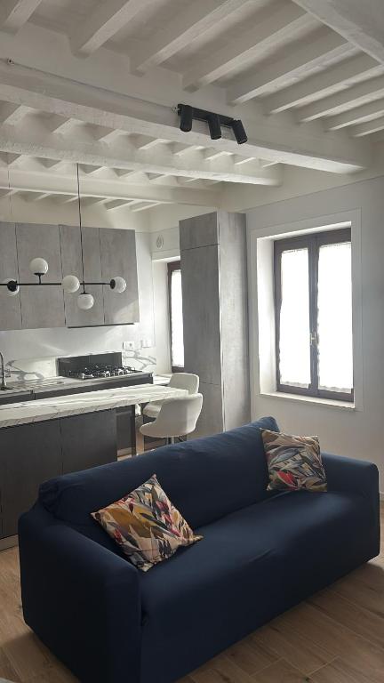 a living room with a blue couch and a kitchen at La terrazza del Papa in Pienza