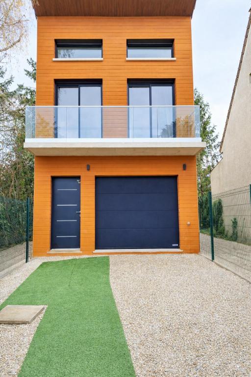 a house with two garage doors and a green yard at VILLA Papillon , maison entière avec jardin in Champigny-sur-Marne