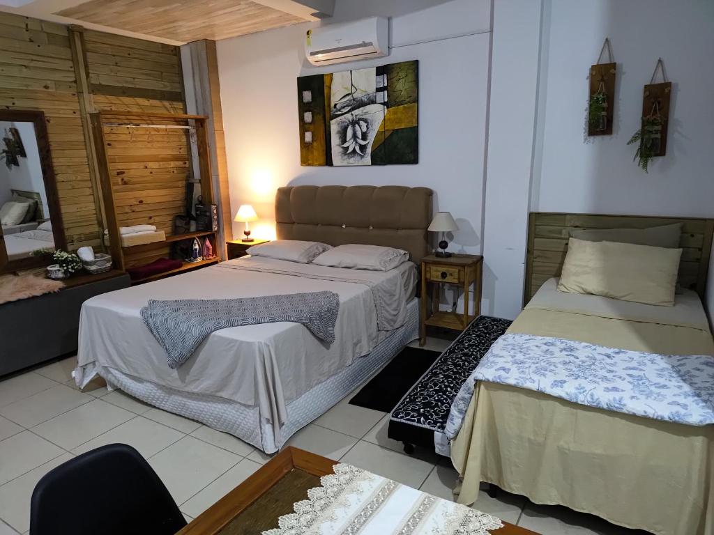 a bedroom with two beds and a chair in it at Estúdio conceito aberto - 3 pessoas in Araranguá