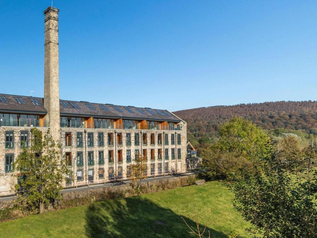 an old building with two chimneys and a grass field at 2 Bed in Keighley oc-83162 in Cononley