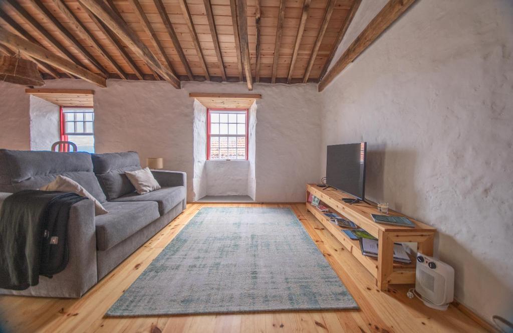 a living room with a couch and a television at Ribeirinha 94 in Ribeirinha