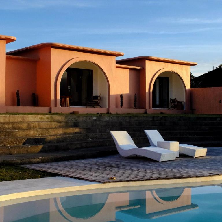 ein Haus mit zwei weißen Stühlen neben einem Swimmingpool in der Unterkunft Ruma Mahavidna in Kintamani