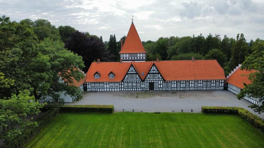 a large building with a red roof in a field at Risinge Herregård Bed & Breakfast in Ullerslev