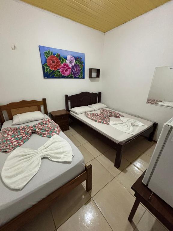 a room with two beds and a painting on the wall at Hotel D'Aldeia Cametá in Cametá