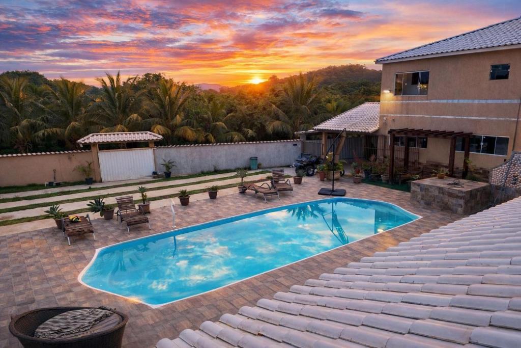 a swimming pool on top of a house with a sunset at Suites Lara Jackson in Saquarema
