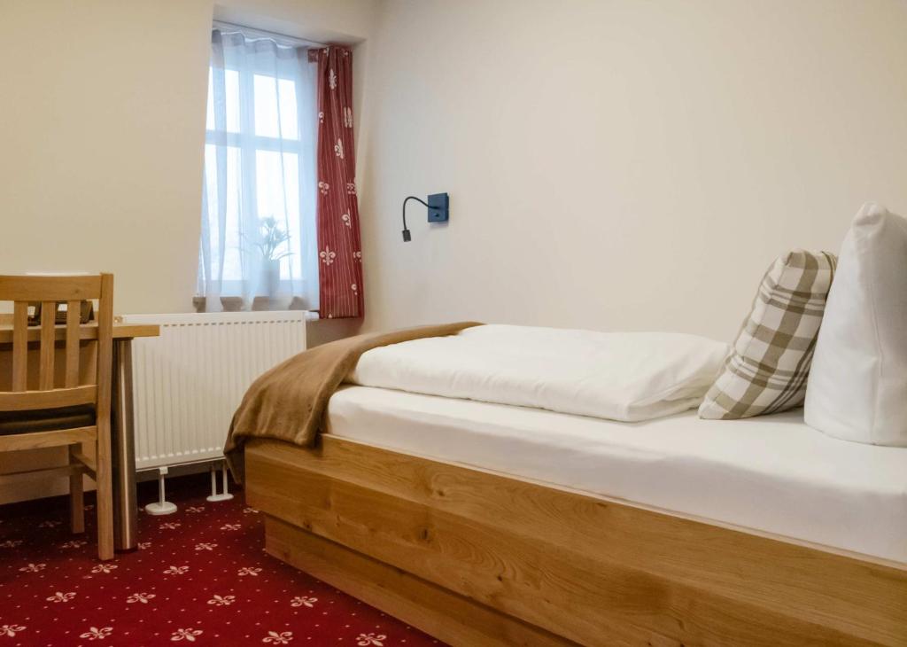 a bedroom with a bed with a desk and a window at Einzelzimmer 13 in Heidenheim