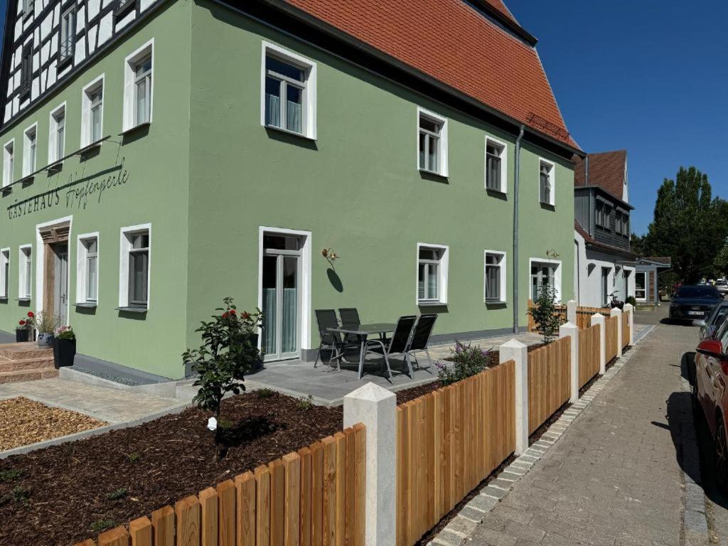 a green building with chairs in front of it at Apartment mit Terrasse "Blumentraum" in Spalt