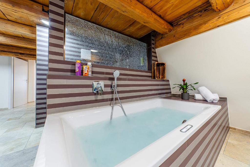 a large bath tub in a room with wooden ceilings at Wellness Apartment Suite "Paradies Suite" in Spalt