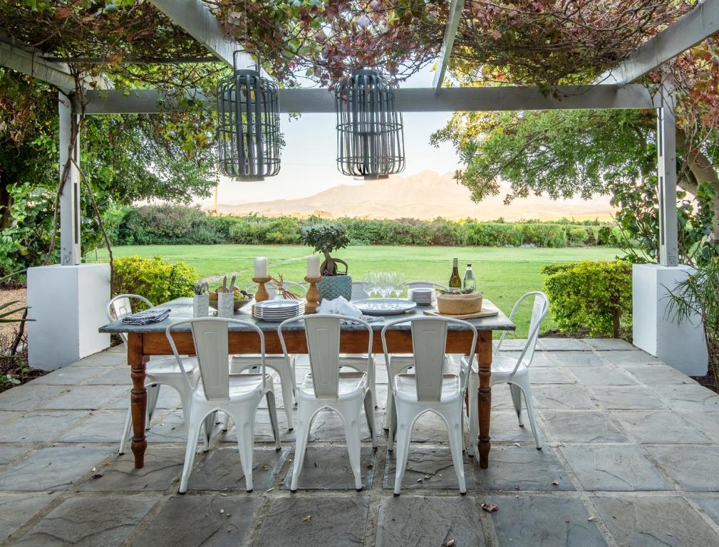 a dining table and chairs on a patio at Stellenbosch Farm Cottage with Mountain Views in Stellenbosch