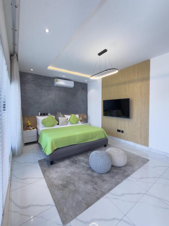a bedroom with a green bed and two ottoman at Luxury Executive Balcony Suite at THE HIDDEN DOMUS I Elmina Suite in Accra