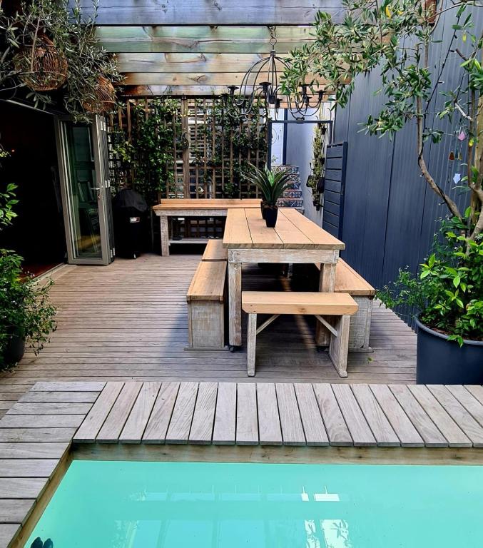 a patio with a table and benches next to a pool at What’s behind the green door! in Cape Town