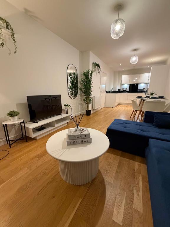 a living room with a blue couch and a table at Prestige London Apartment Balcony Views in London