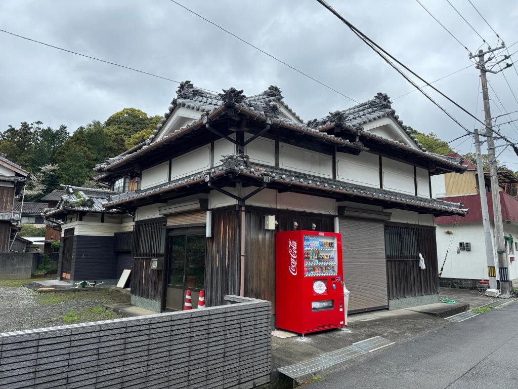 a small house with a red coke machine in front of it at ゲストハウス虎のいえ in Sukumo